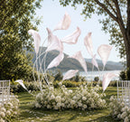 Handcrafted organza calla lily sculpture surrounded by white flowers, creating a luxury wedding ceremony centerpiece in an outdoor garden setting with lake and mountain views.